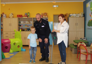 Adaś z funkcjonariuszem Policji podczas ćwiczeń przechodzenia przez jezdnię (ćwiczenia w sali)