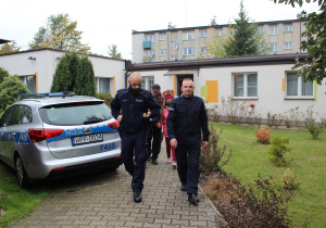 Funkcjonariusze Policji, w tle przedszkolaki z wychowawcami w drodze na przejście dla pieszych