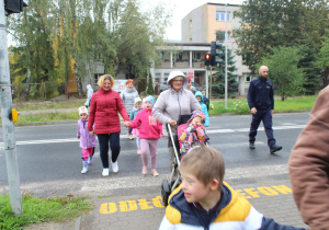 Przedszkolaki podczas przechodzenia przez ulicę pod opieką funkcjonariusza Policji i wychowawców