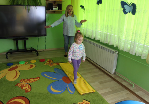 Ania na sensorycznym torze przeszkód, w tle pani Małgosia