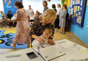 Mikołaj pod opieką Pani Małgosi odciska paluszek w Kronice przedszkola