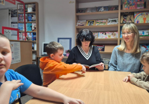 Grudniowe spotkanie czytelnicze - na zdjęciu przedszkolaki słuchają opowiadania i oglądają ilustracje ptaków
