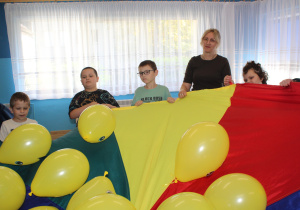 "Tydzień Budowania Relacji" - na zdjęciu przedszkolaki w trakcie zabawy z chusta animacyjną i żółtymi balonami