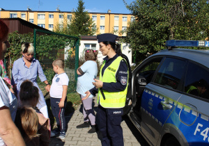 Pogadanka przy radiowozie policyjnym na temat bezpieczeństwa - na zdjęciu uczestnicy zajęcia