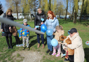 Przedszkolaki wręczają niebieskie balony mieszkańcom miasta