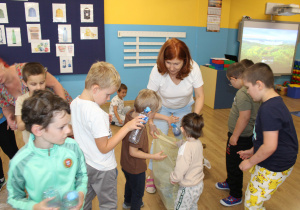 Sprzątanie świata - Marysia i Mikołaj wyrzucają plastikowe butelki.