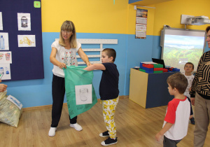 Sprzątanie świata - Krzyś wrzuca szkło do zielonego worka.