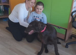 Zajęcia z dogoterapii - na zdjęciu Mikołaj z Panią Anetą głaszczą psa