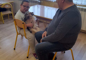 Zajęcia z dogoterapii - na zdjęciu Szymon z pieskiem i z terapeutą.