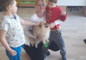 Zajęcia z dogoterapii - na zdjęciu Pani Aneta, Michał i Yaroslav głaszczą pieska.