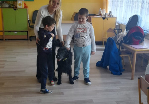 Zajęcia z dogoterapii - na zdjęciu Kuba, Krzyś i Pani Aneta głaszczą psa.
