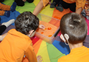 Dzień pomarańczowy - na zdjęciu przedszkolaki poszukują skarbów w pomarańczowym ryżu