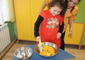 Dzień pomarańczowy - na zdjęciu Julia łowi plastry pomarańczy