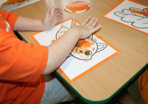 Dzień pomarańczowy - na zdjęciu dziecko podczas malowania paluszkami