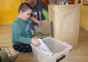 Tydzień higieny - na zdjęciu Mikołaj wyjmuje ubrania z kartonowej pralki