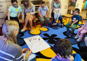 Dzieci z Paniami tworzą plakat "Pomocna dłoń"