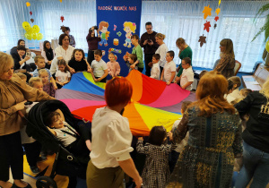 Przedszkolaki z paniami i laureatami konkursu biorą udział w zabawie z chustą animacyjną