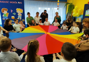 Przedszkolaki z paniami i laureatami konkursu biorą udział w zabawie z chustą animacyjną