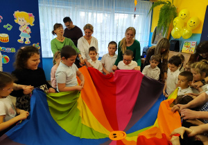 Przedszkolaki z paniami i laureatami konkursu biorą udział w zabawie z chustą animacyjną