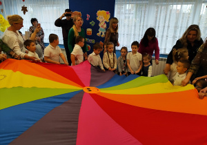 Przedszkolaki z paniami i laureatami konkursu biorą udział w zabawie z chustą animacyjną