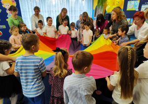 Przedszkolaki z paniami i laureatami konkursu biorą udział w zabawie z chustą animacyjną