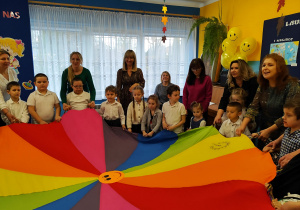 Przedszkolaki z paniami i laureatami konkursu biorą udział w zabawie z chustą animacyjną