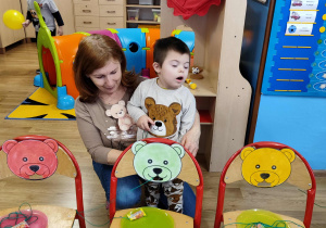 Antoś przeciąga cukierka na sznureczku, przez pyszczek misia.