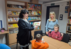 Grudniowe spotkanie czytelnicze - na zdjęciu Pani Ewa otrzymuje świąteczną kartkę