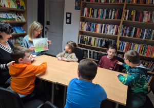 Grudniowe spotkanie czytelnicze - na zdjęciu przedszkolaki słuchają opowiadania i oglądają ilustracje ptaków