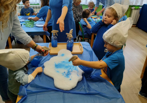 Dzień niebieski - dzieci z grupy II kolorują chmurki spryskiwaczem z niebieską farbą.