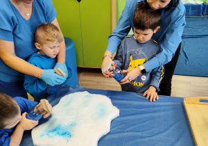 Dzień niebieski - Antoś z Mikołajem kolorują chmurki spryskiwaczem z niebieską farbą.