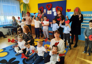 Dzień babci i dziadka - przedszkolaki z paniami śpiewają piosenkę z serduszkami.