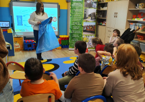 Pani z PGK prezentuje niebieski worek na papier