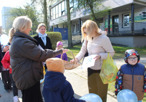 Przedszkolne obchody Dni Autyzmu - na zdjęciu przedszkolaki wręczają niebieskie serduszka przechodniom
