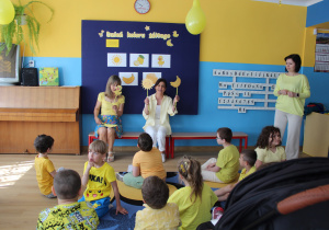 Żółty dzień w przedszkolu - przedszkolaki siedzą na dywanie, słychają piosenki śpiewanej przez p. Kasię i Kingę