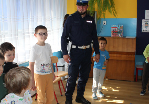 "Bezpieczna droga do przedszkola" - na zdjęciu funkcjonariusz Policji z przedszkolakami w trakcie zabawy ruchowej