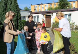 "Sprzątanie Świata" - na zdjęciu przedszkolaki dumnie sprzątają przedszkolny ogród